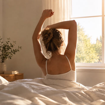 Woman stretching in bed in a bright, sunny bedroom