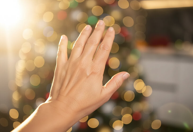 Hand reaching out towards a blurred festive background with lights